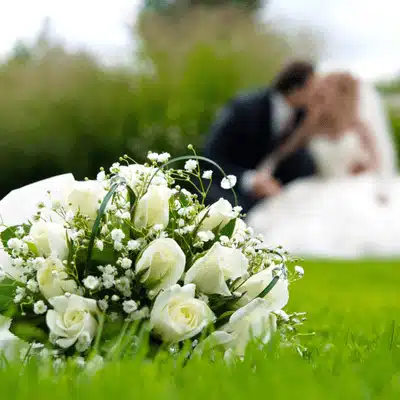 A close-up of a bridal bouquet with a couple in the background, showing the best time to get married in Texas