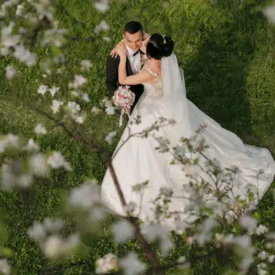 A bride and groom share a kiss beneath blossoming trees—spring is the best time to get married in Texas