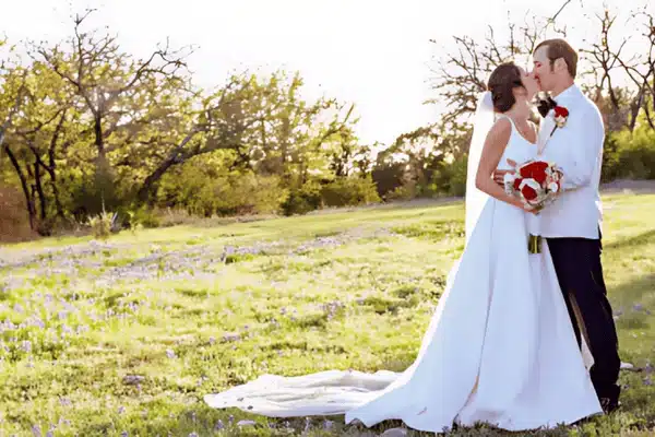 A couple kisses in a flower-dotted field, showing the best time to get married in Texas