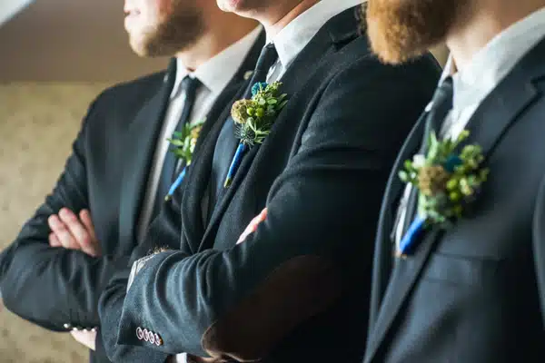 Close-up of groomsmen in matching suits with boutonnieres, showcasing stylish groom prep before ceremony