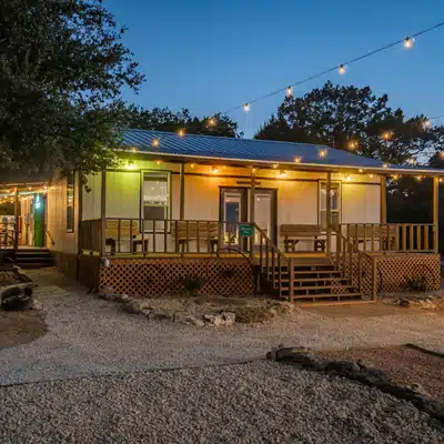 Cozy cabin with porch lights glows at dusk, welcoming teams for relaxing retreat accommodations tonight