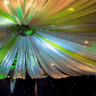 Fabric drapes and twinkling lights cascade from venue ceiling, creating luminous celebratory atmosphere for receptions