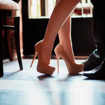 Close-up couple dancing; high heels on polished floor, exploring types of ambience for romantic settings