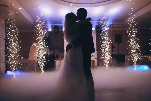 Bride and groom share first dance amid indoor sparklers and fog, dramatic reception lighting effects