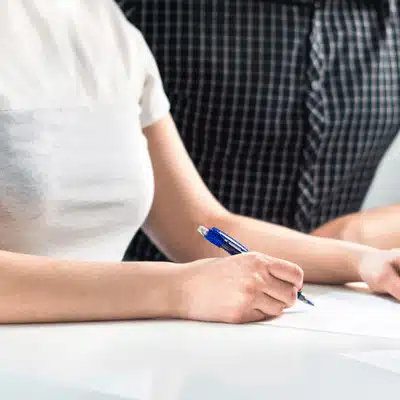 Bride signs marriage documents at counter, partner beside her, planning a wedding in texas today