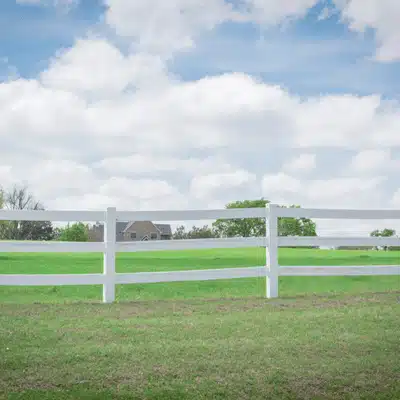 White ranch fence borders green pasture under blue sky at tuscan texas countryside wedding location