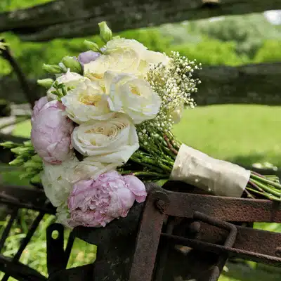 Pastel wedding bouquet rests on rustic farm equipment at charming tuscan texas ranch venue outdoors