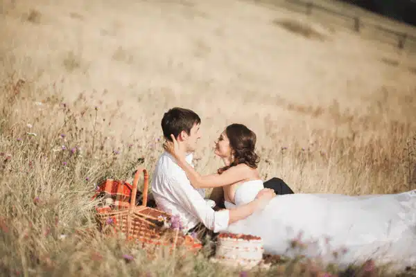 Bride and groom cuddle during picnic in wildfield, symbolizing romance at affordable ranch wedding venues
