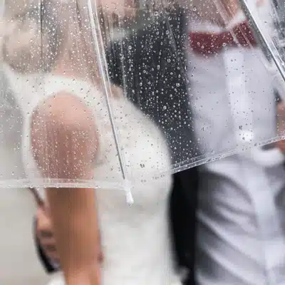 Raindrops bead on clear umbrella shielding couple at wedding venue central texas, romantic outdoor ceremony