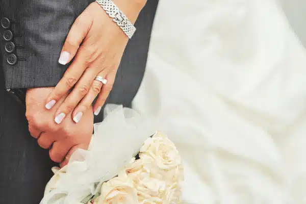 Photo shows couple holding hands with bouquet, highlighting ranch wedding venues in texas ceremony details